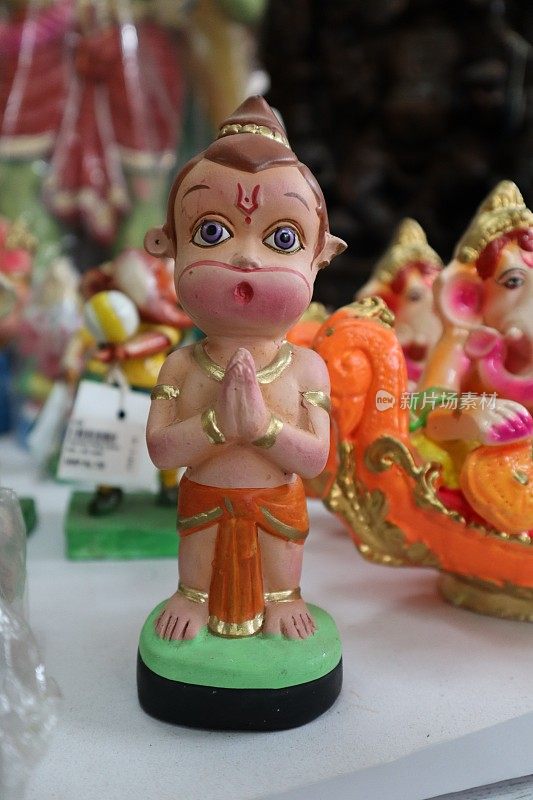 这是一个可爱的娃娃，用粘土材料制成，手绘上鲜艳的颜色，描绘了年轻的哈努曼神，在印度排灯节、Dasara、Lakshmi puja和Durga puja等宗教节日期间受到崇拜。